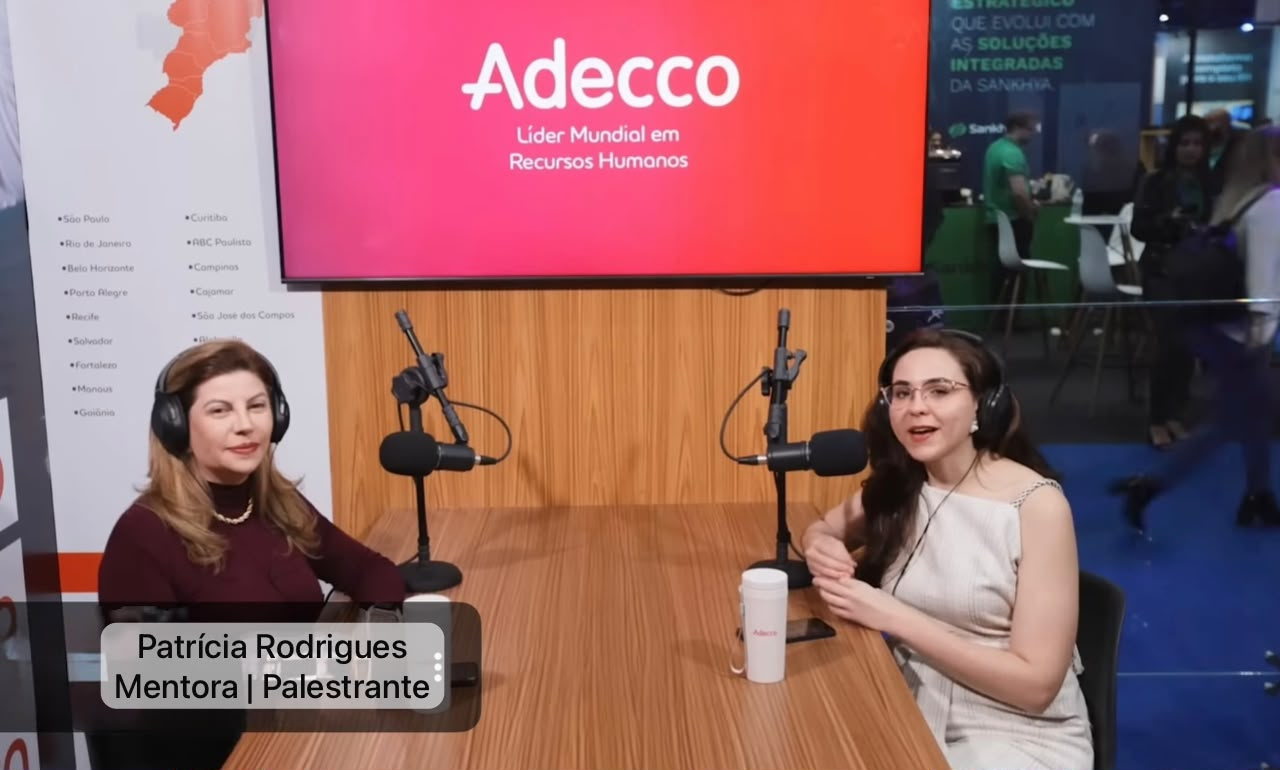 Patrícia Rodrigues participando de uma gravação de entrevista em estúdio, com microfone e fones de ouvido.